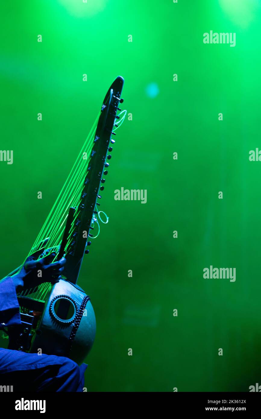 Artist performing traditional wooden harp, kora during event, in colorful stage lights. Stock Photo