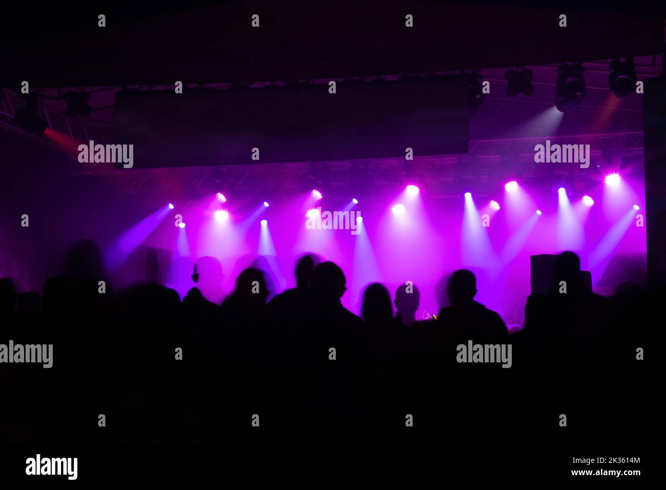 Blurred crowd at concert with bright colorful stage lights Stock Photo
