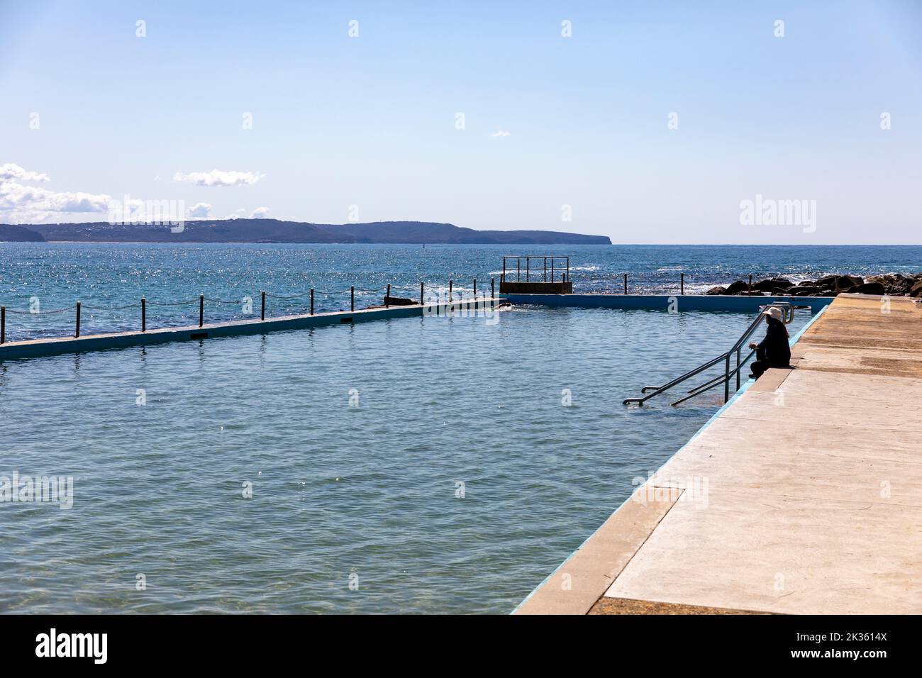 Palm Beach swimming rock pool with lady sitting beside the pool and view of the Central Coast of New South Wales,Australia Stock Photo