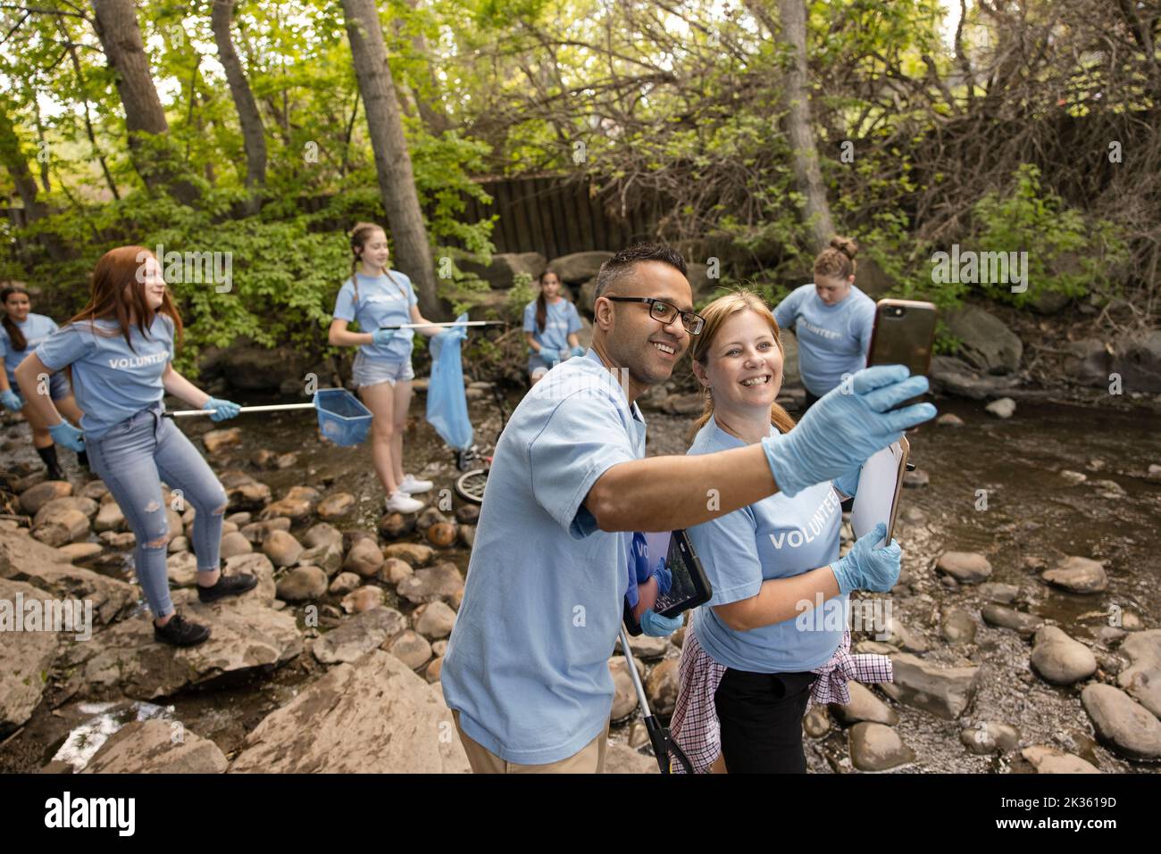 Cheerful teachers taking selfie at river cleanup Stock Photo