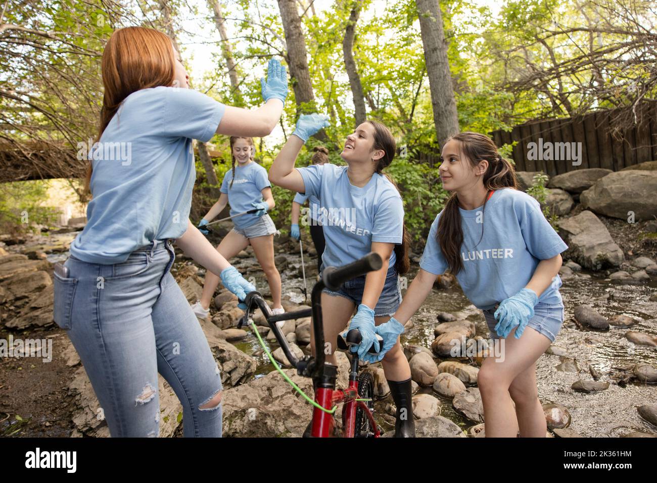 Cheerful student volunteers giving highfive at river cleanup Stock Photo