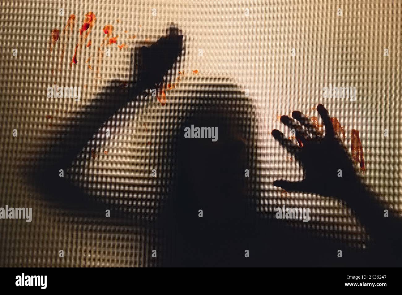 Horror, halloween background - Shadowy figure behind glass holding a knife with blood Stock Photo