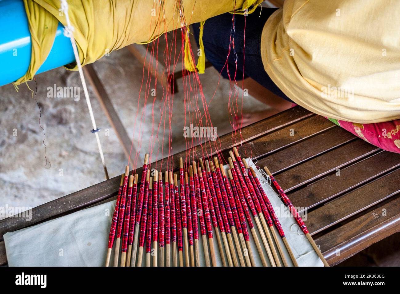 A long stick of red dyed silk for weaving silk clothing laid out on a table. Stock Photo
