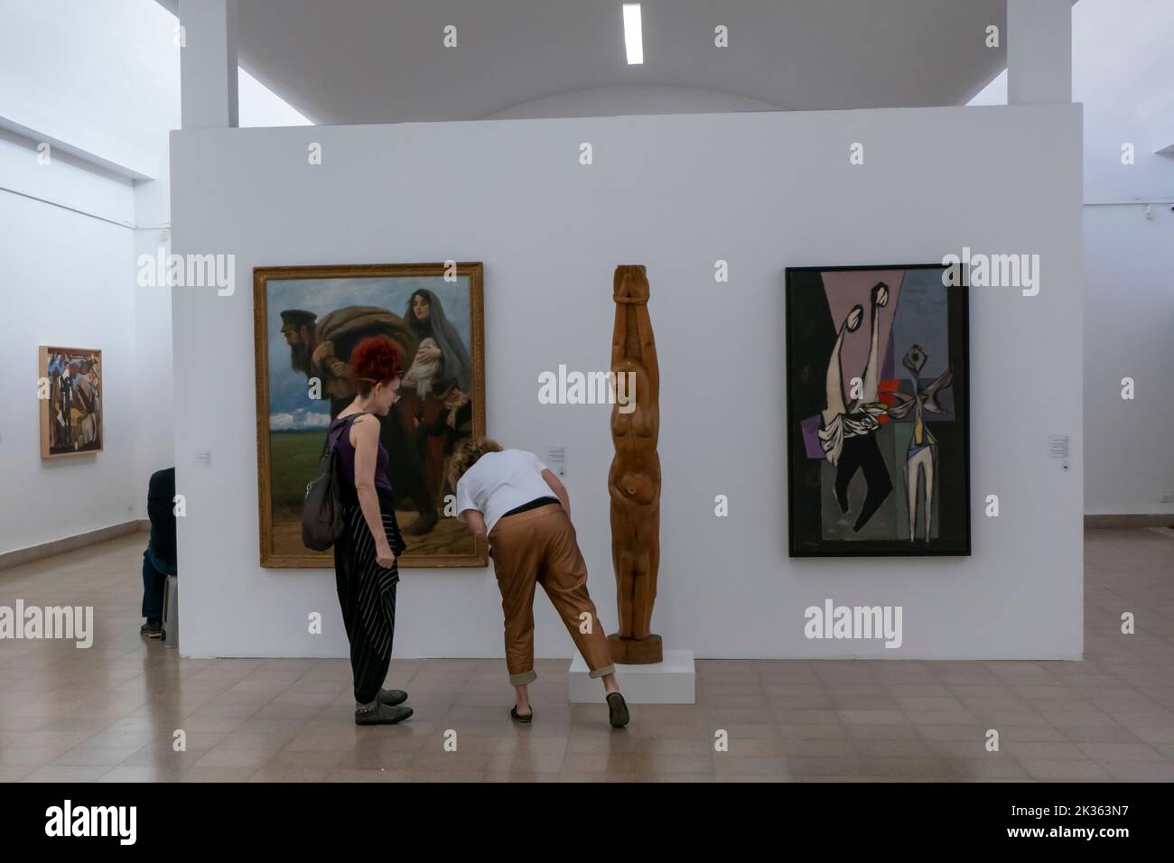 Visitors view artwork by Israeli artists inside the Mishkan Museum of Art located on the grounds of Kibbutz Ein Harod Meuhad in Israel. The museum was designed by architect Samuel Bickels, inaugurated in 1948 and was the first rural museum run by a kibbutz. Stock Photo