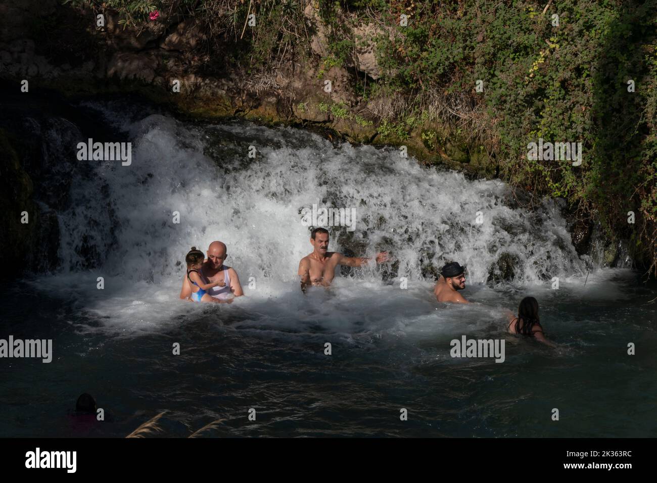 People bath in a small waterfall at a natural spring water pool in Gan HaShlosha National Park also known by its Arabic name Sakhne in Israel Stock Photo