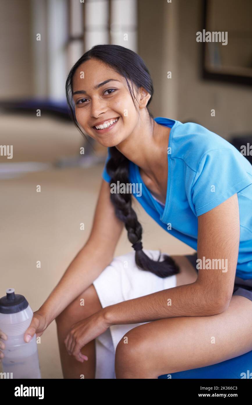 Theres nothing like the feeling you have after a good workout. Portrait of a girl in a blue t-shirt having a rest and smiling in the gym. Stock Photo