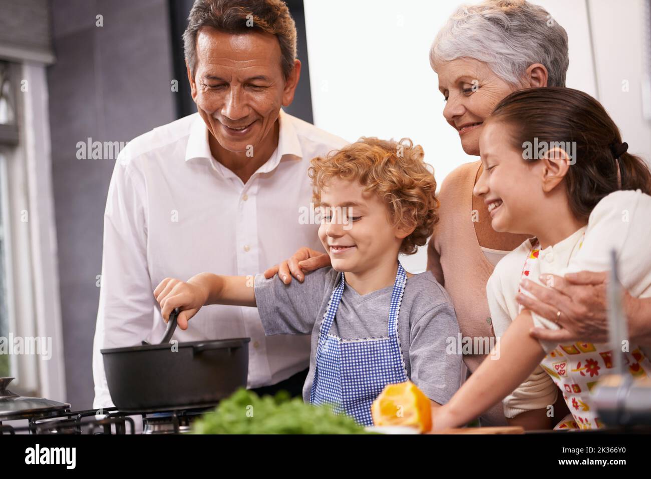 Passing down family recipe secrets. A brother and sister helping to make dinner at their grandparents house. Stock Photo