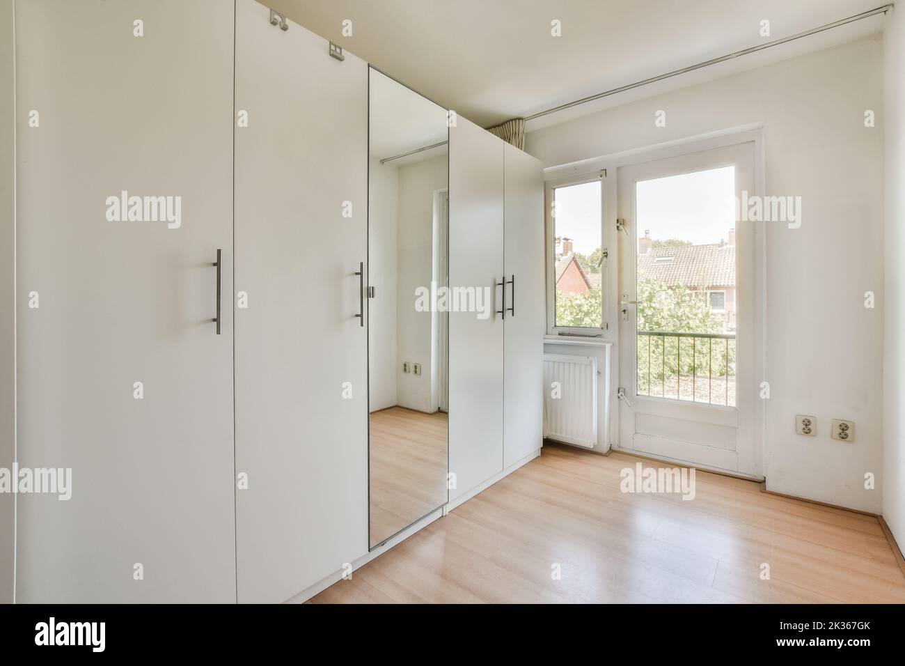 Comfortable bed near window and balcony door in light mansard bedroom at home Stock Photo