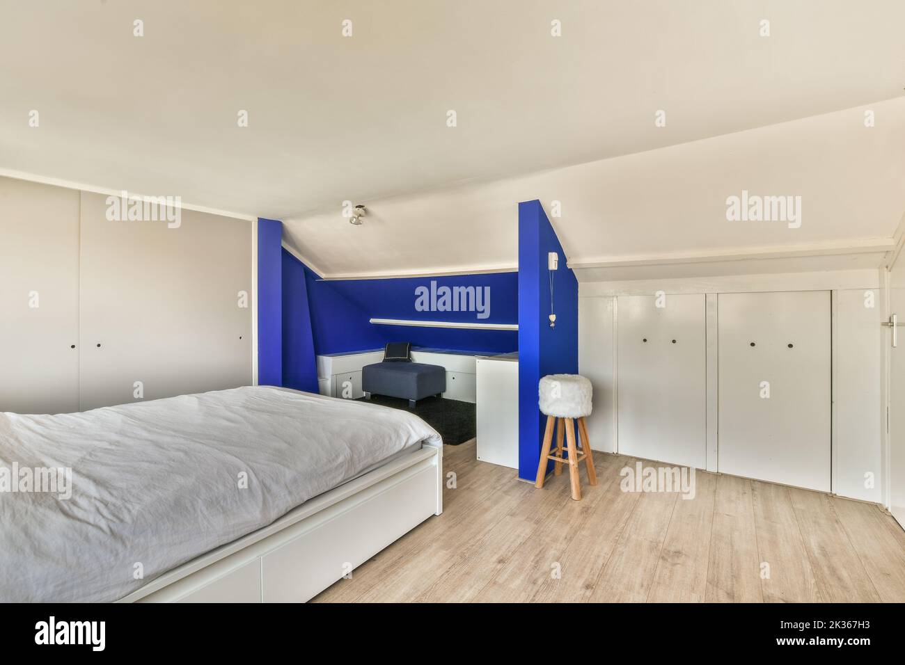 Comfortable bed near window and balcony door in light mansard bedroom