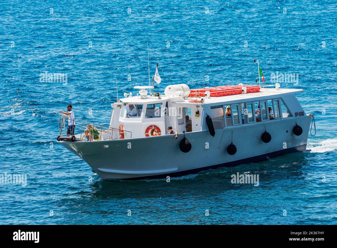 Ferry with tourists on board is arriving in the small port of Tellaro village, Mediterranean sea, Lerici, Gulf of La Spezia, Liguria, Italy, Europe. Stock Photo