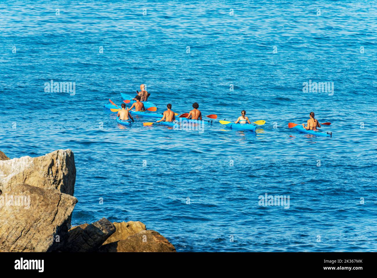 Large group of kayakers in the blue Mediterranean Sea, on a sunny summer day. Tellaro village, Gulf of La Spezia, Liguria, Italy, southern Europe. Stock Photo
