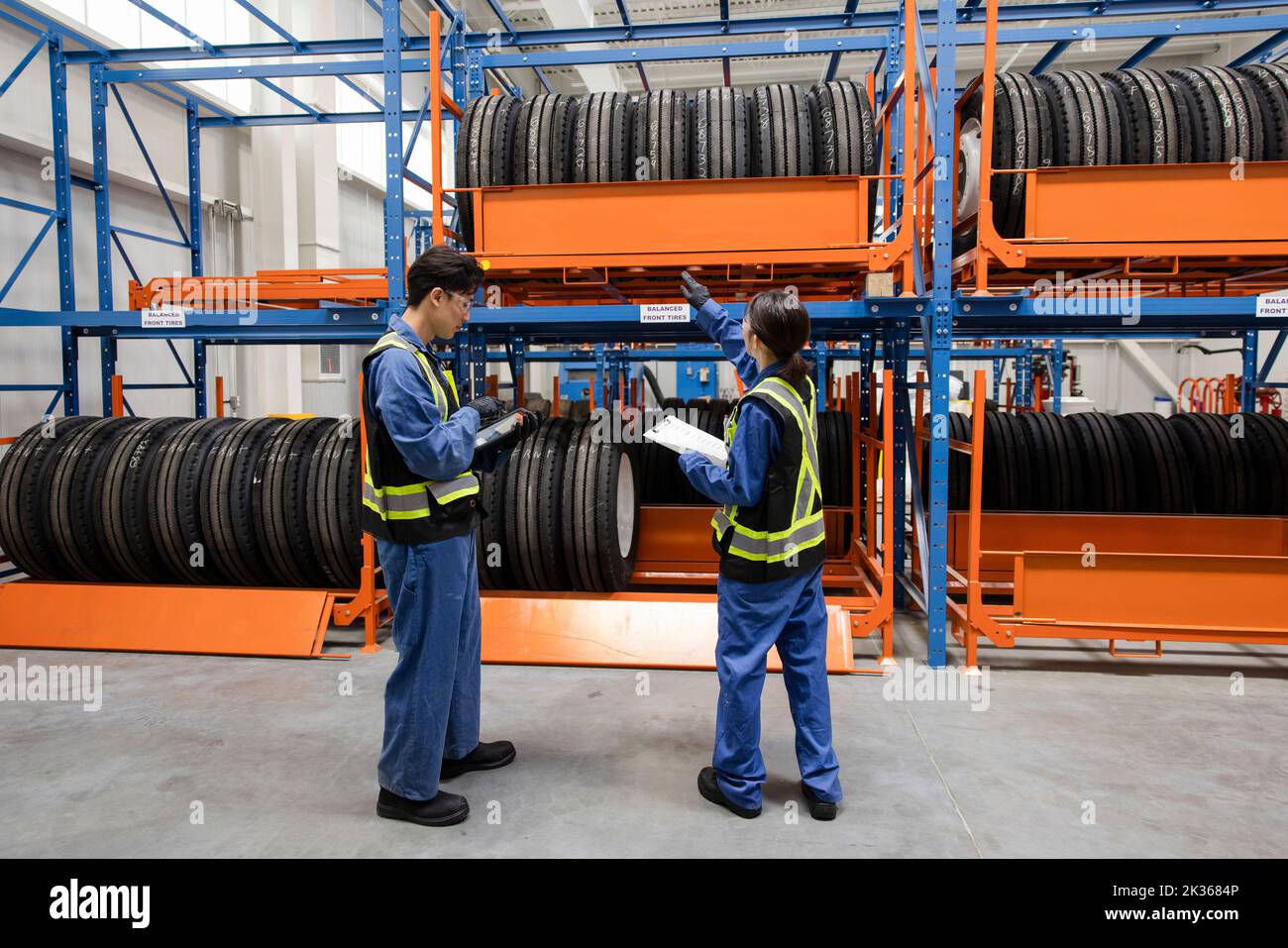 Mechanics looking at tires on racks in maintenance facility Stock Photo
