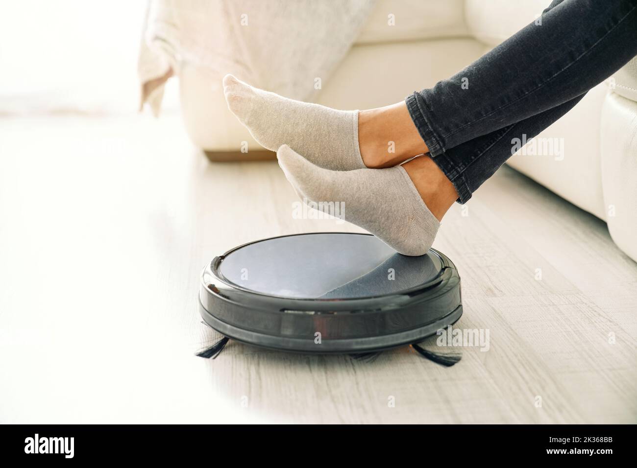 Woman placing hands on robotic vacuum cleaner Stock Photo