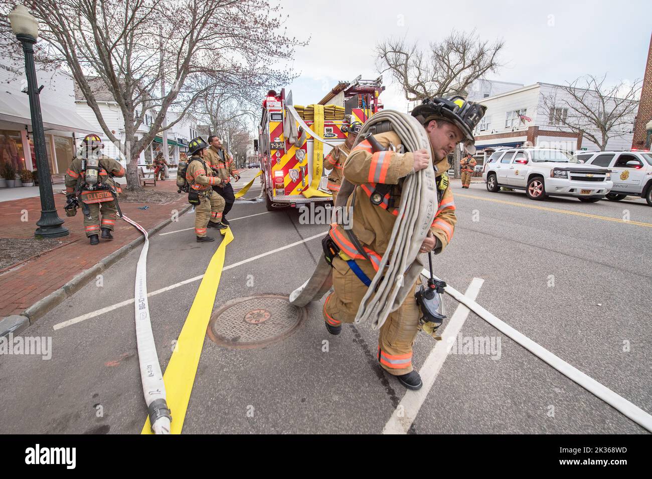 A firefighter works to pull hose from a fire truck as the Southampton Fire Department, assisted by units and members from the Bridgehampton, Sag Harbo Stock Photo