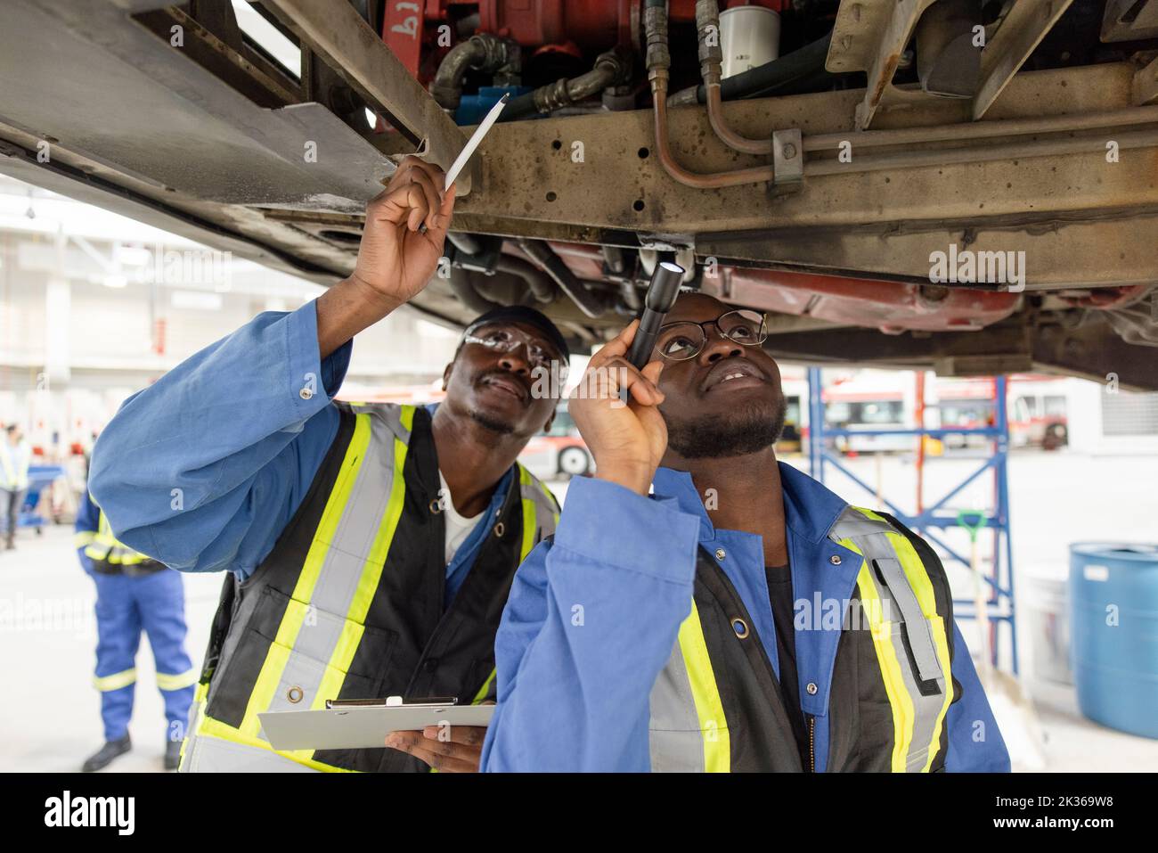 Male mechanics under bus in maintenance facility Stock Photo Alamy