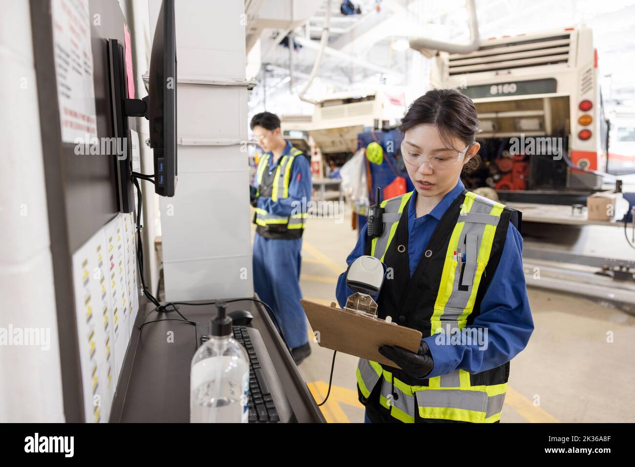 Female engineer scanning paperwork in bus maintenance facility Stock