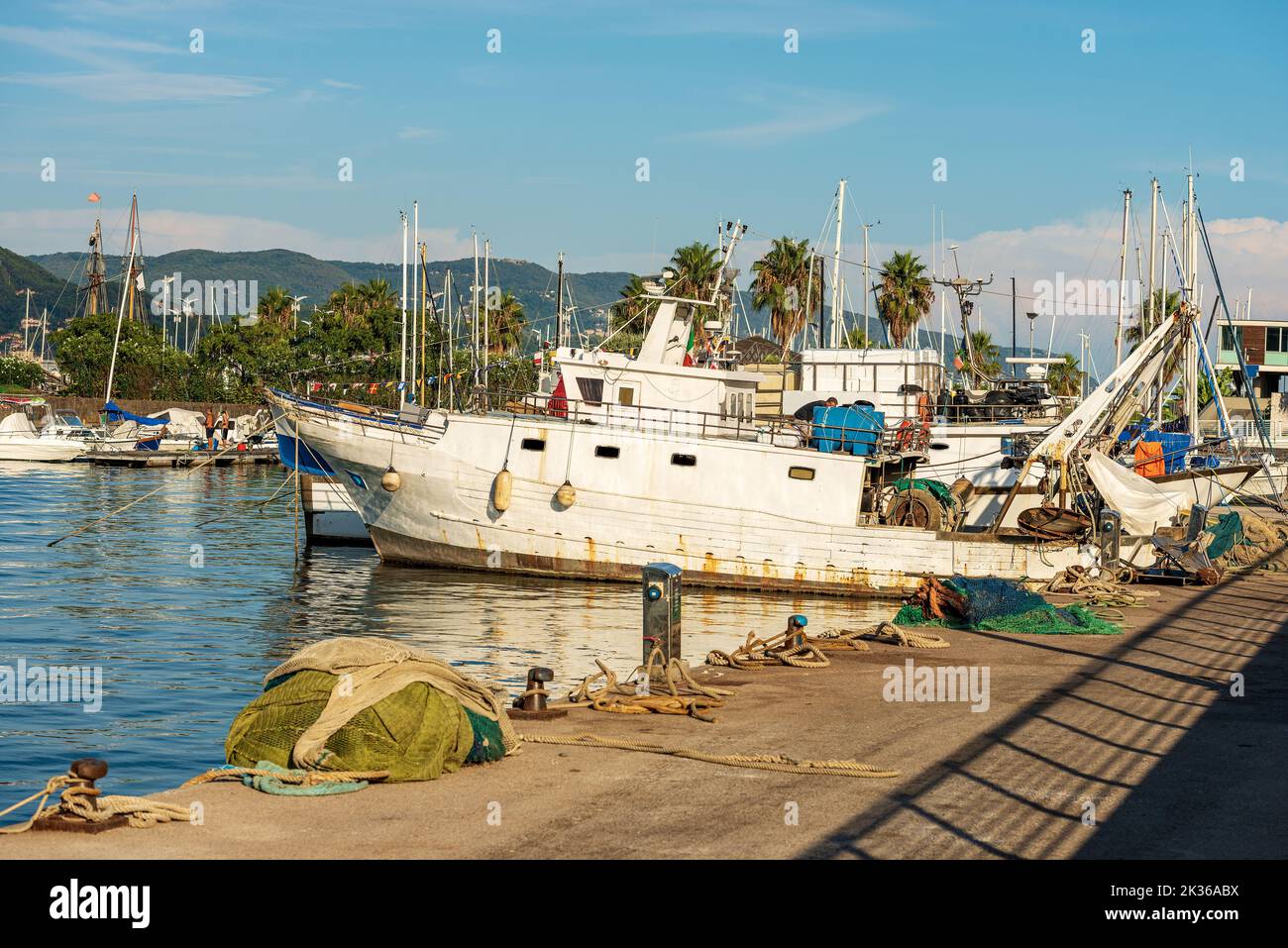 Fishing boats used for trawling (trawler), quayside with nets, ropes and moorage bollards. Port of La Spezia town, Gulf of La Spezia, Liguria, Italy. Stock Photo