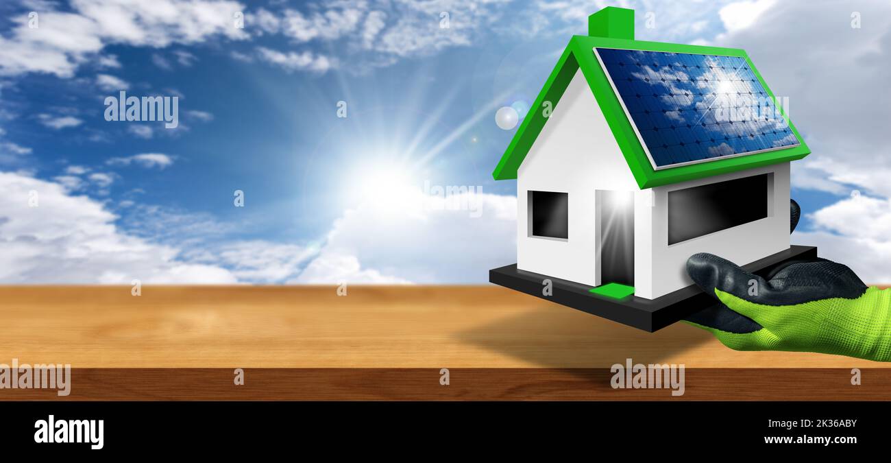 Gloved hand holding a small model house with solar panels on the roof on a wooden workbench with a blue sky with clouds and sunbeams on background. Stock Photo