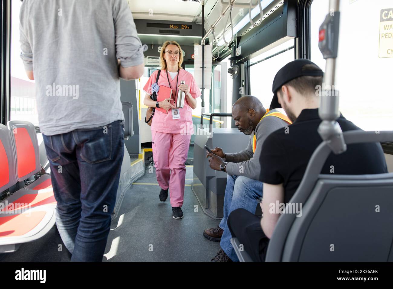 Female nurse in pink scrubs boarding public transit bus Stock Photo Alamy