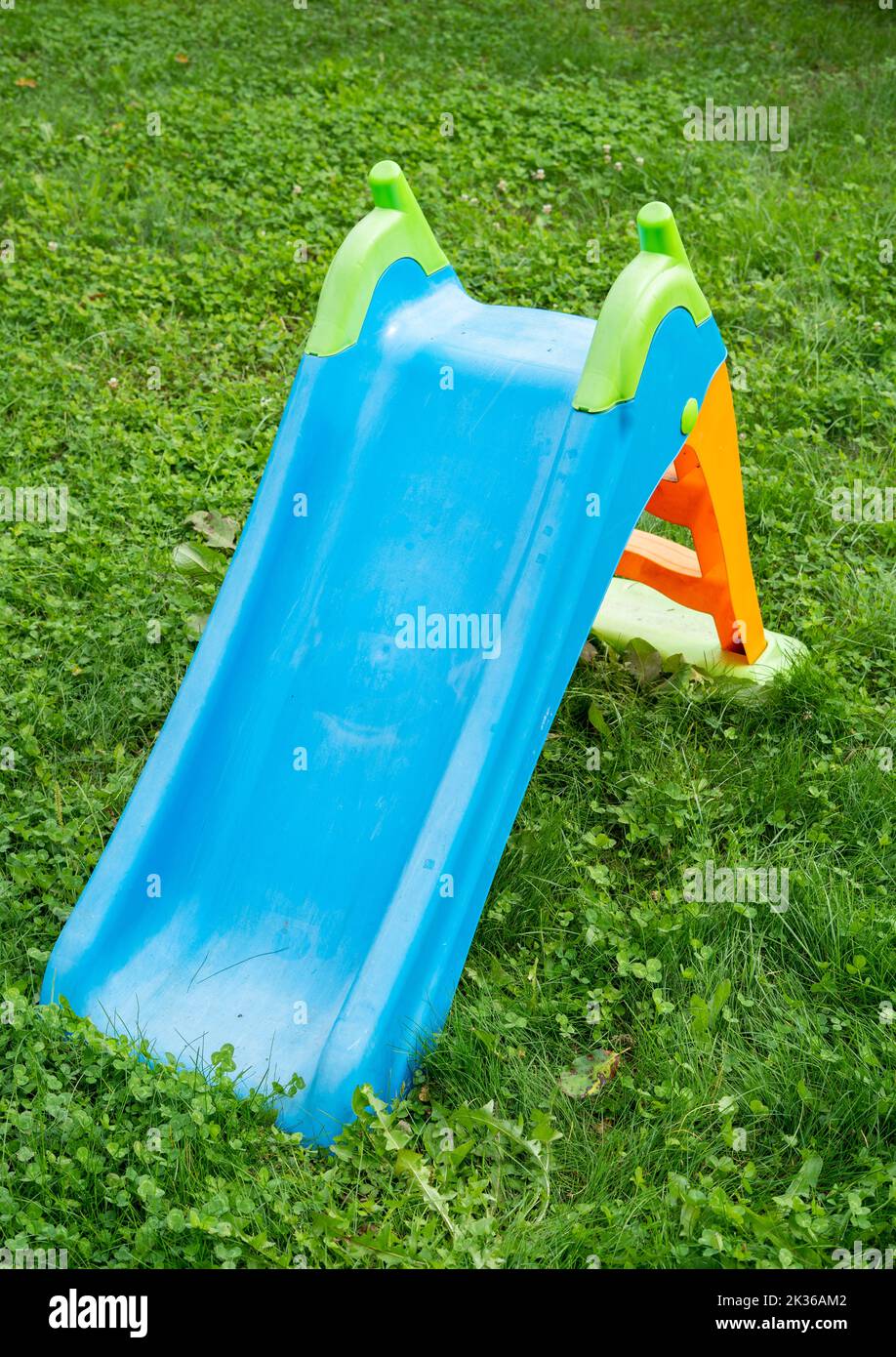 A plastic slide in the grass in the park in the children's playground for little children Stock