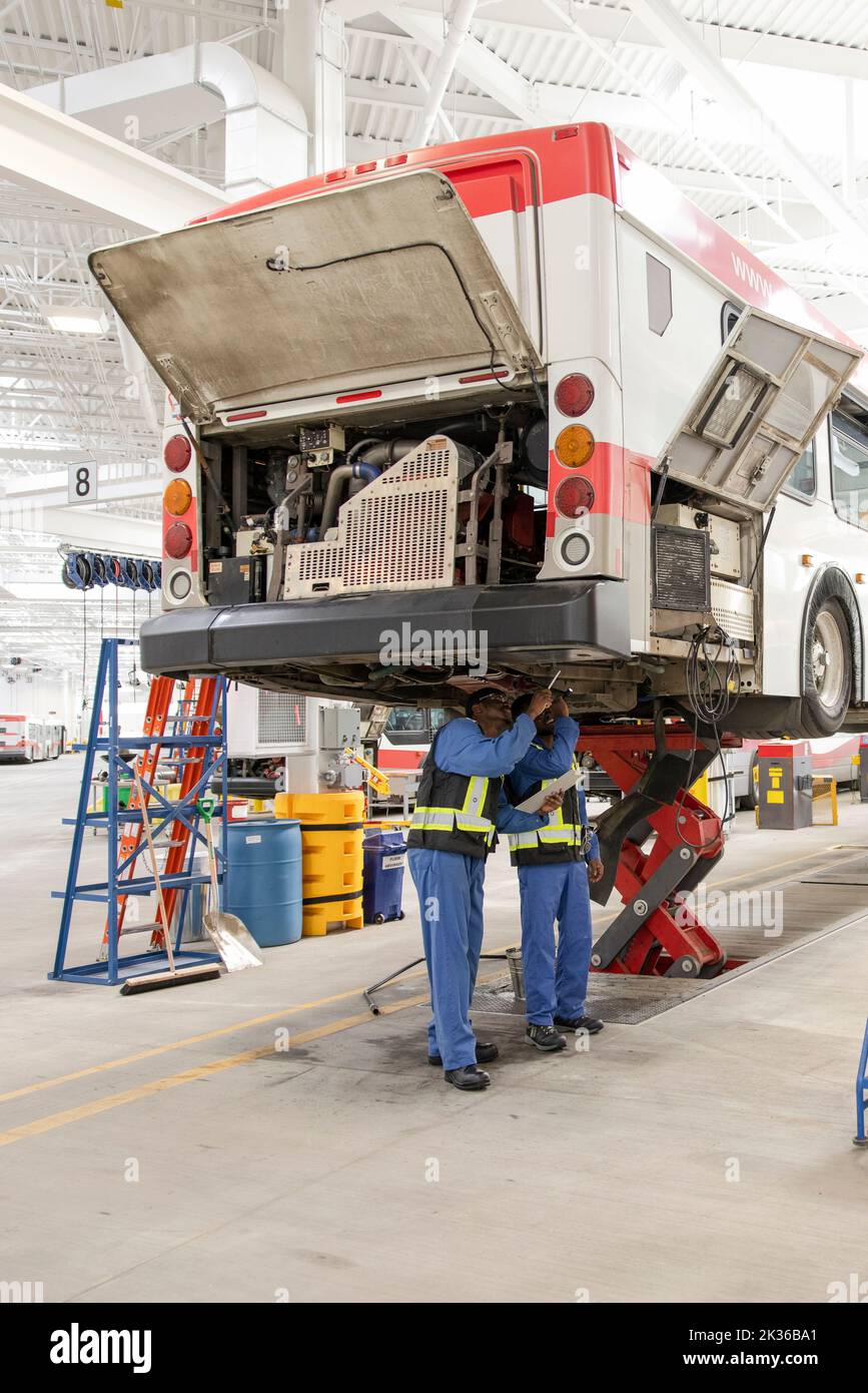 Male mechanics working under bus in maintenance facility Stock Photo