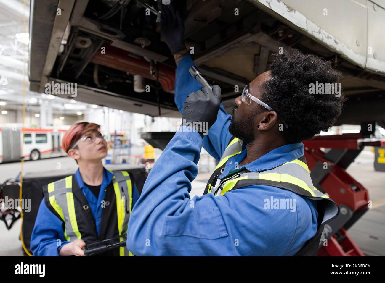 Mechanics working under bus in maintenance facility Stock Photo Alamy