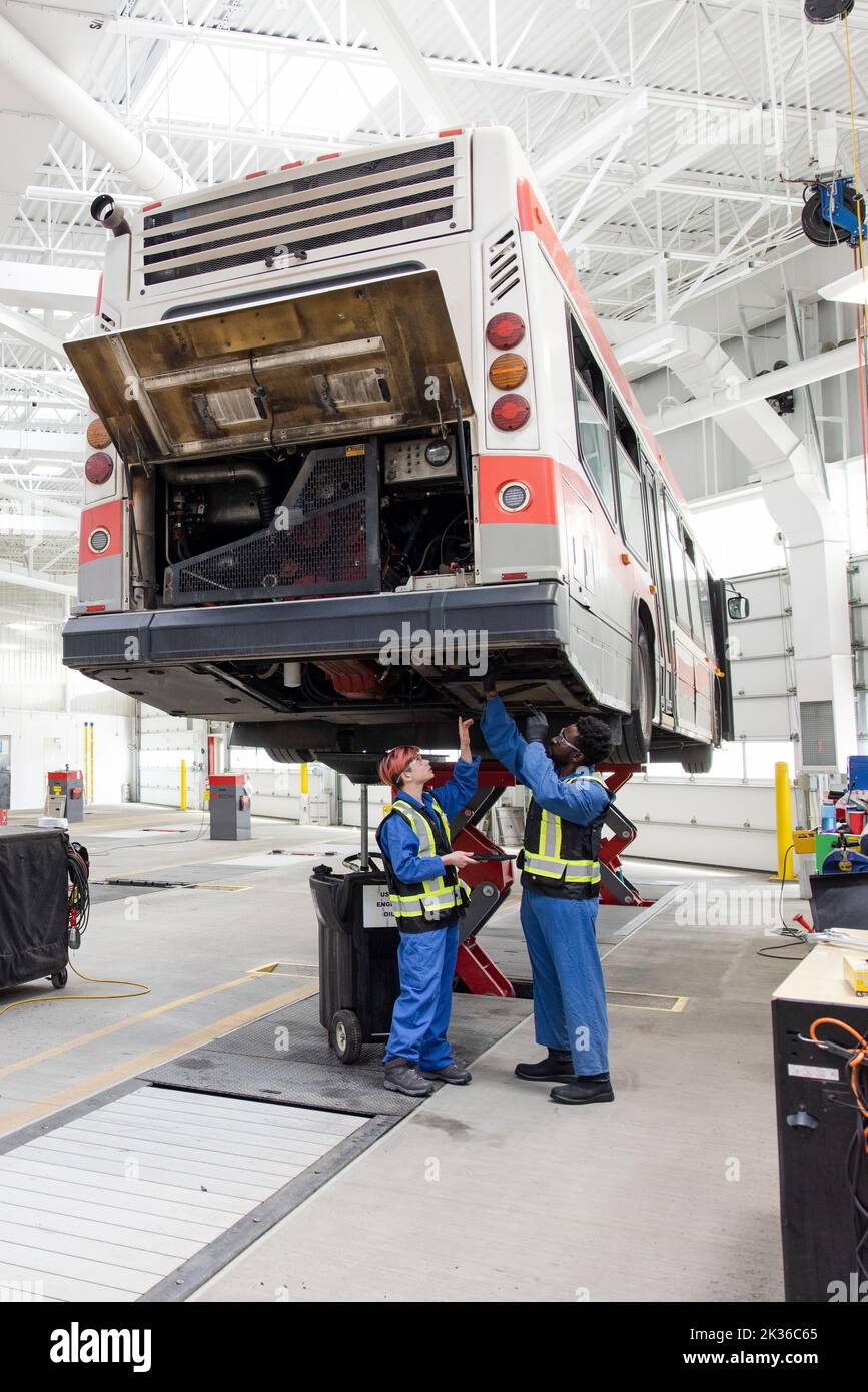 Mechanics working under bus in maintenance facility Stock Photo Alamy