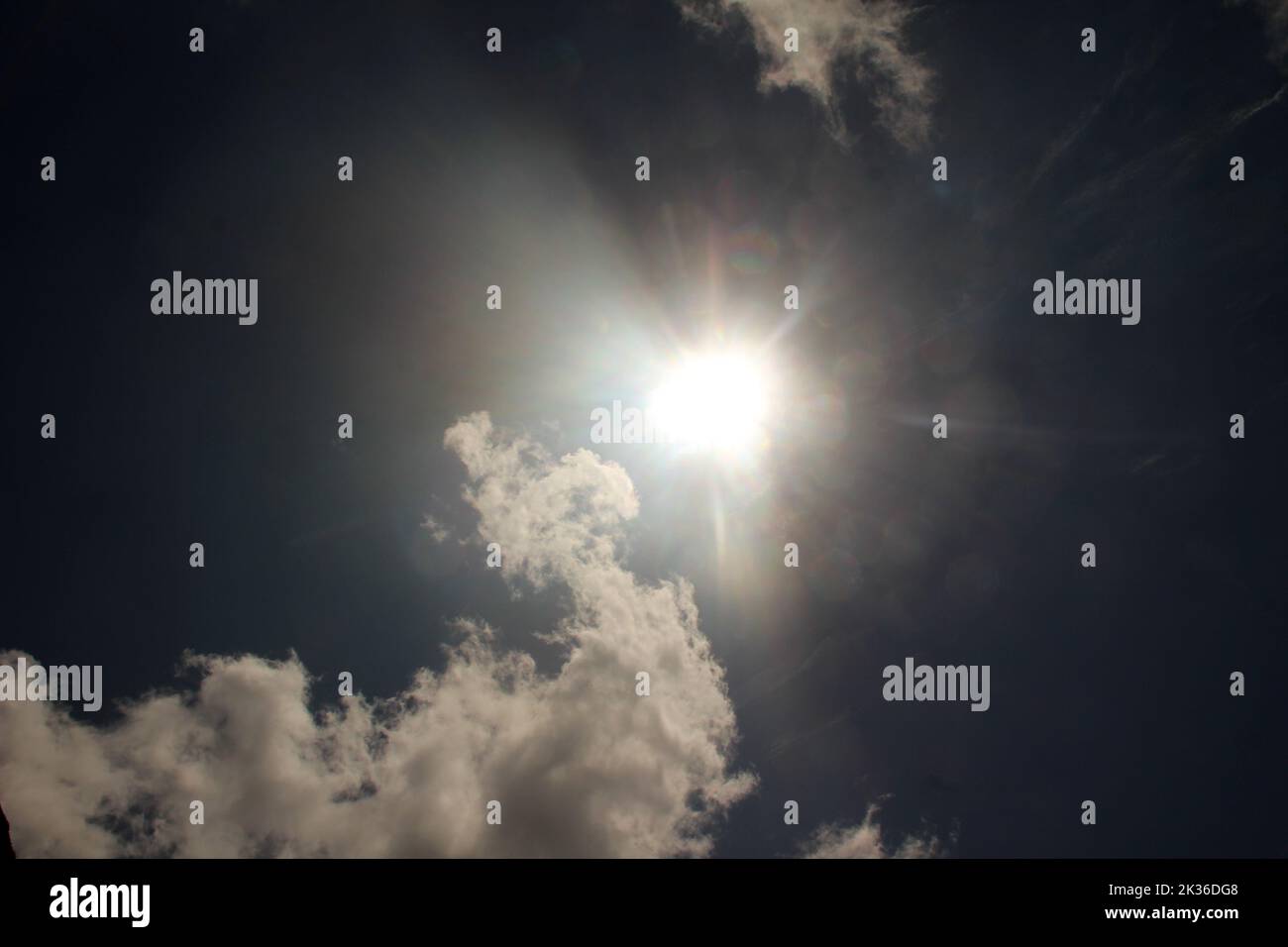 A blue sky with the sun shining in white clouds Stock Photo - Alamy