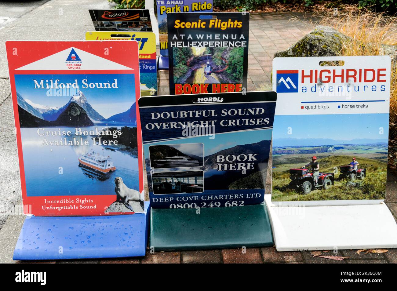 A set of local travel display boards outside a tourist travel office at Te Anau, a small lakeside town on South Island, New Zealand.  Te Anau lies on Stock Photo