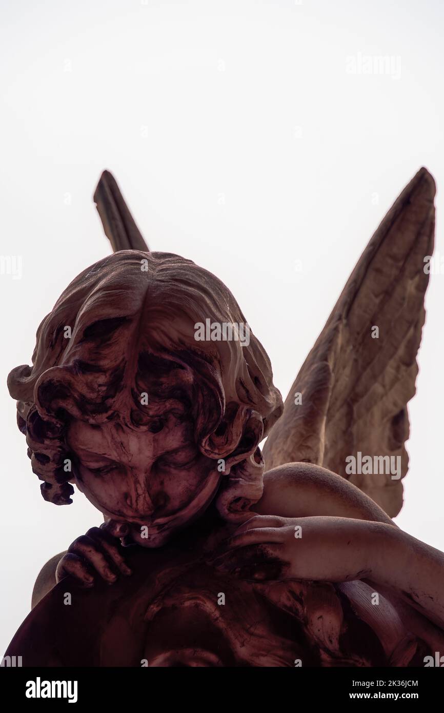 Statue figure of an angel with wings, against a white background. Stock Photo