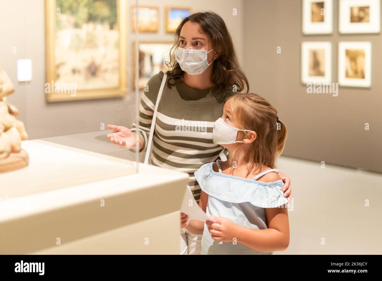 Mother and daughter in masks with guide enjoying expositions in museum ...
