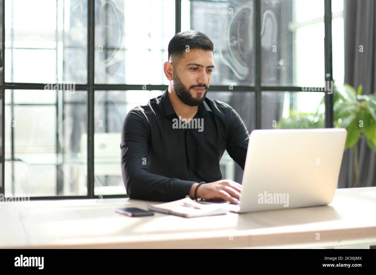 Focused young man wearing using laptop on keyboard, writing email or message Stock Photo