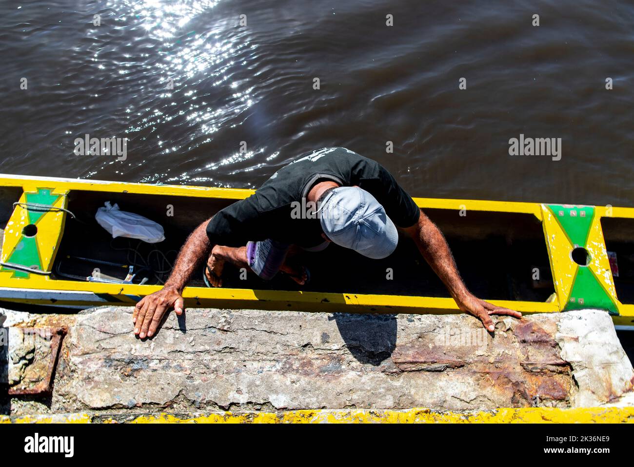 The high-angle view of a fisherman getting into the canoe with the help ...