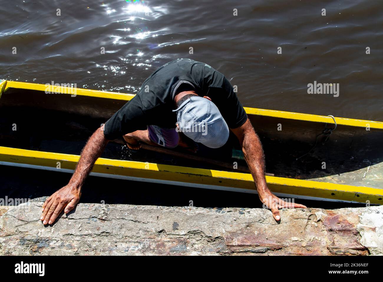 The high-angle view of a fisherman getting into the canoe with the help ...
