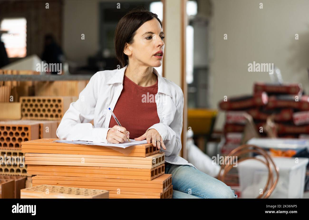 Interested brunette making notes while planning home renovation Stock Photo
