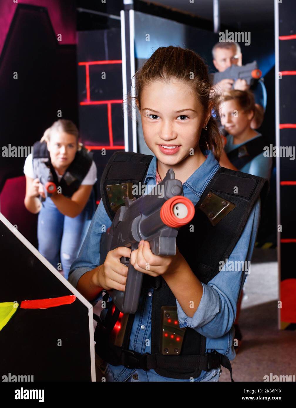 Portrait of teenager girl with laser gun having fun with her family on
