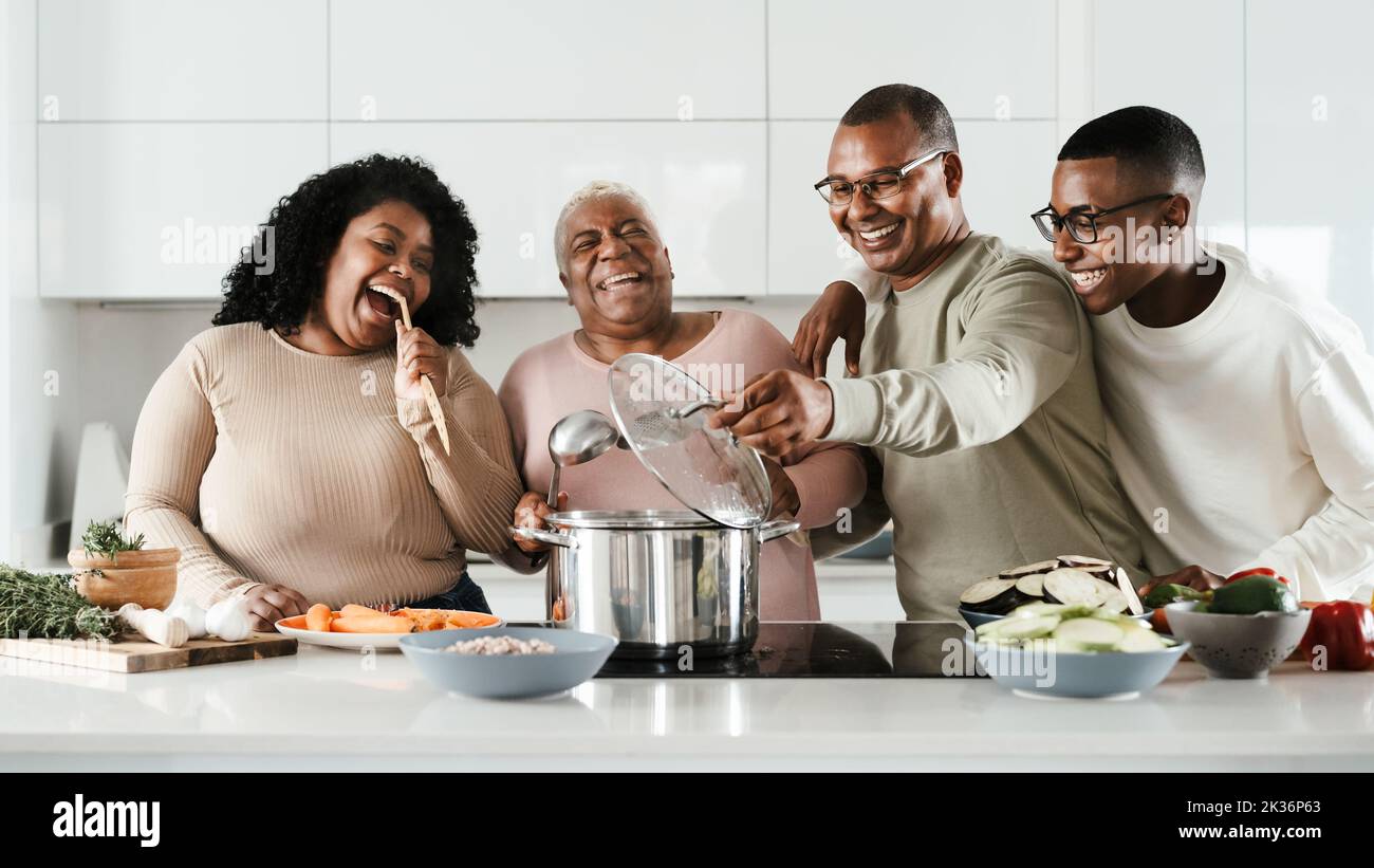 Happy Hispanic family having fun cooking together in modern kitchen - Food and parents unity concept Stock Photo