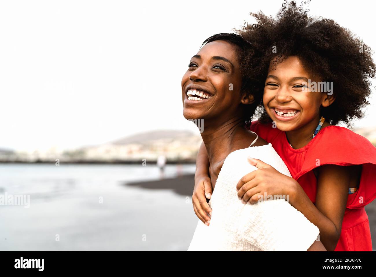 Happy African mother and daughter having fun on the beach during vacations - Lovely family lifestyle concept Stock Photo