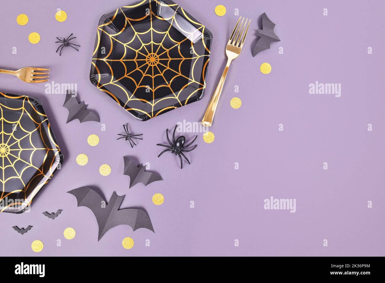 Halloween party flat lay with spider web plates, spiders and confetti on violet background with copy space Stock Photo