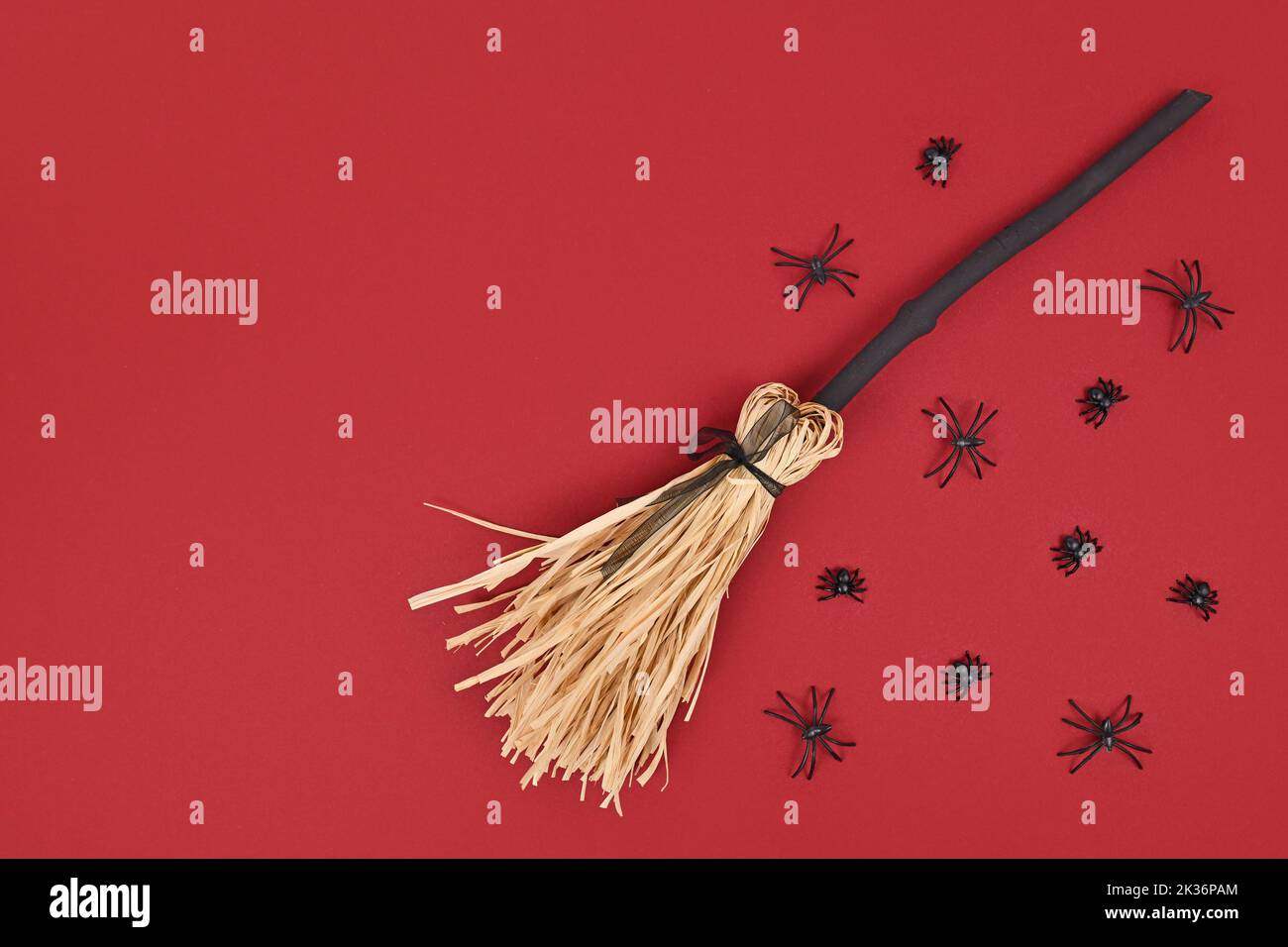 Halloween witch broom and spiders on dark red background with copy space Stock Photo