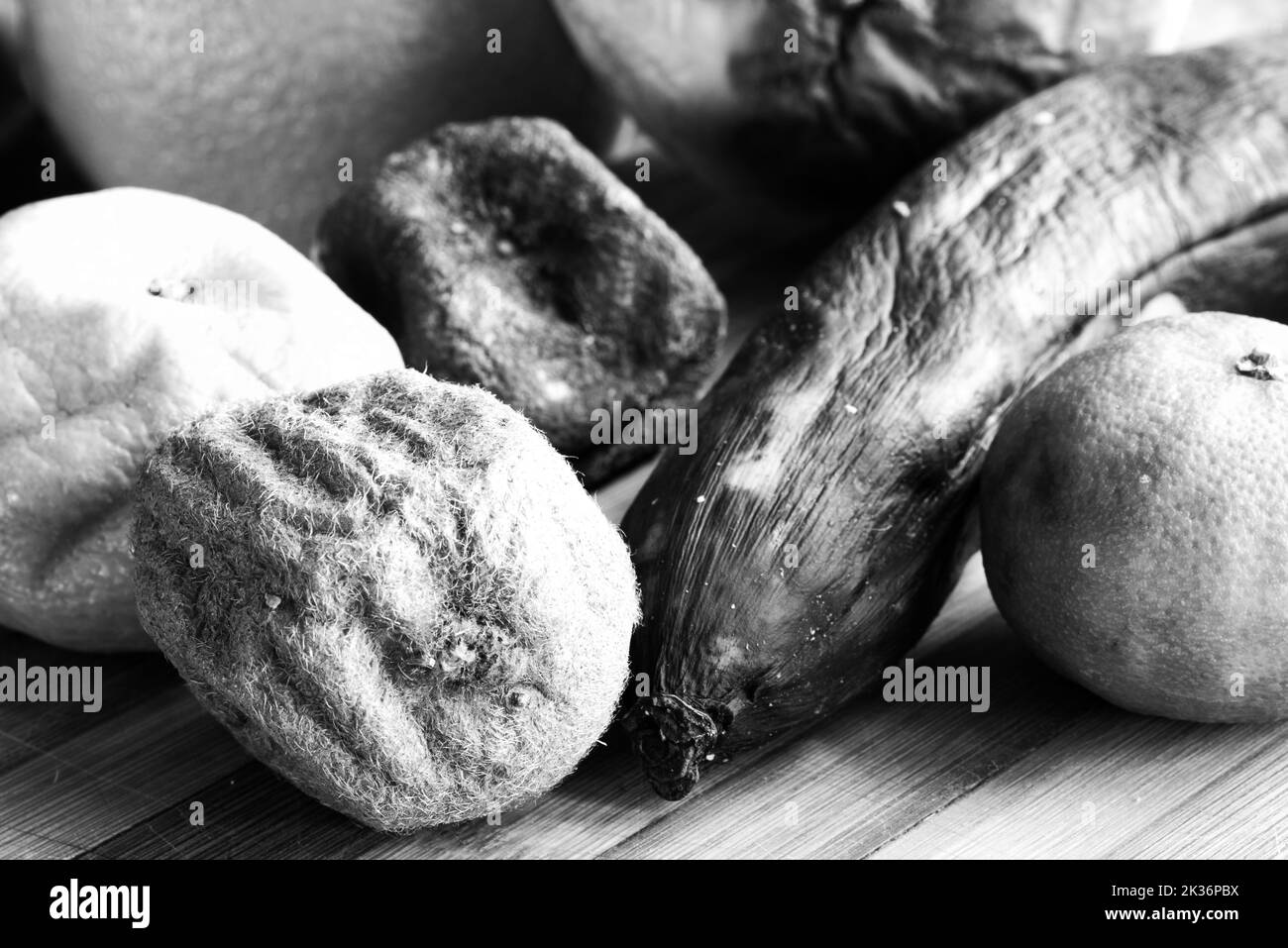 Rotten fruit on a bamboo board in close-up. Old citrus fruit. Spoiled food. Stock Photo