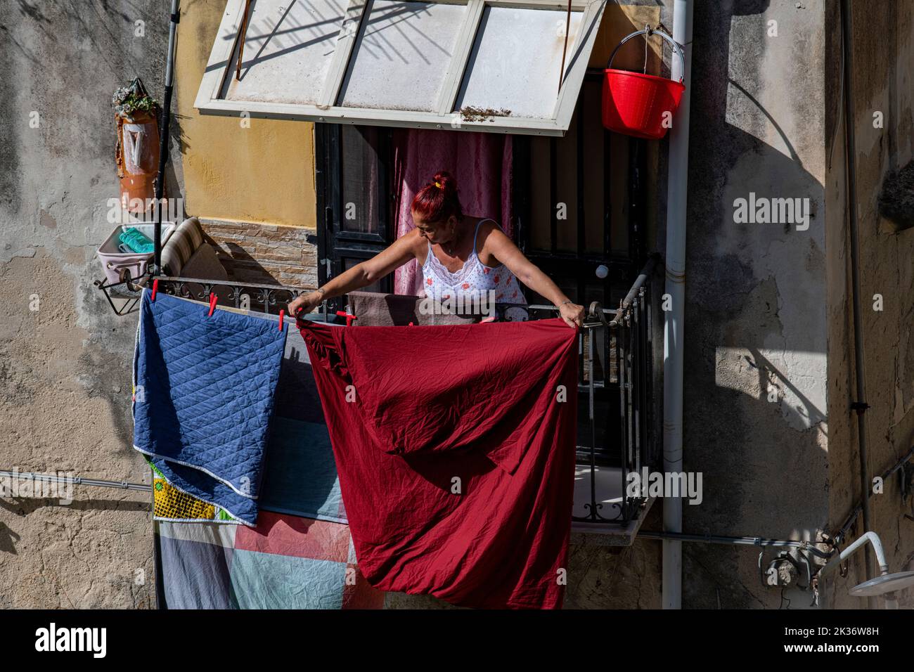 An Italian lady with red hair hangs out her washing to dry in the city of Ragusa in Sicily, Italy Stock Photo