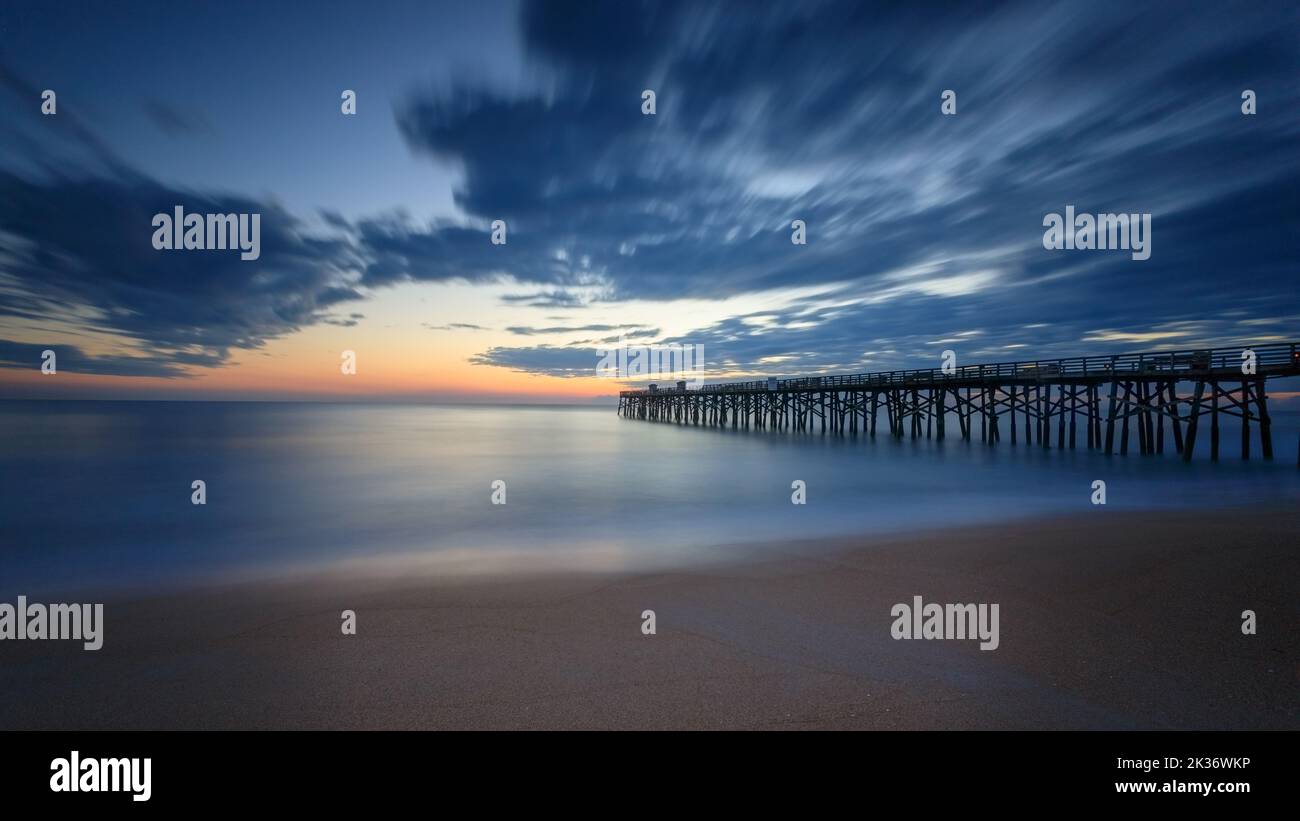 A beautiful sunrise over the Atlantic Ocean with a wooden pier in the ...
