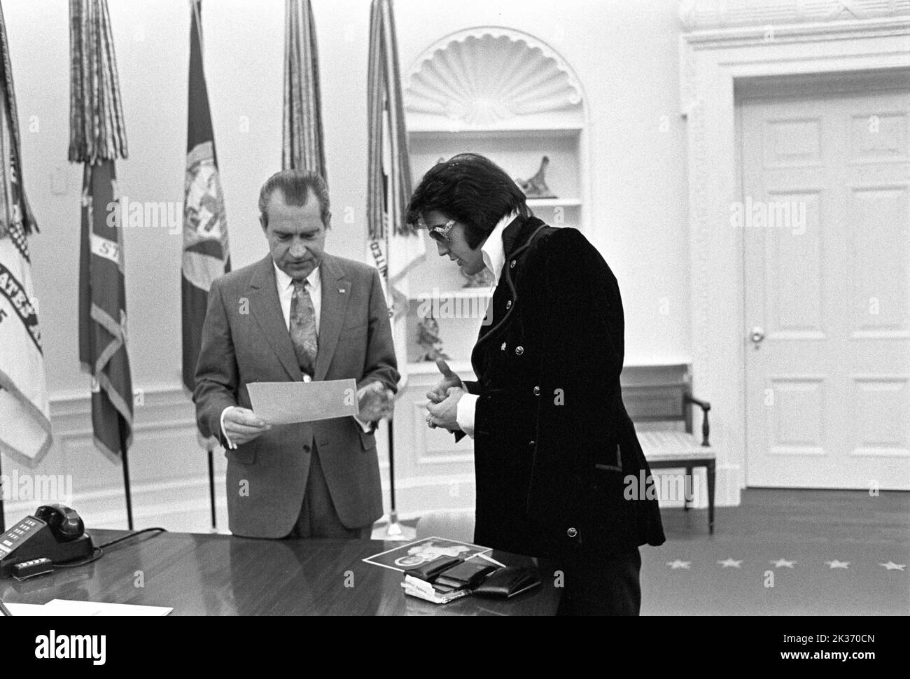 Richard Nixon and Elvis Presley in the Oval Office on December 21, 1970 - Elvis is showing his family photos. Stock Photo