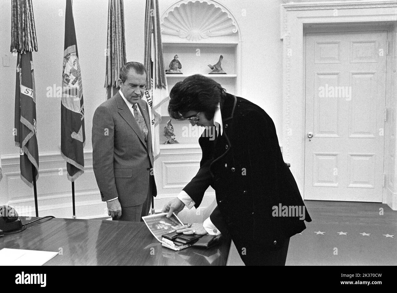 Richard Nixon and Elvis Presley in the Oval Office on December 21, 1970 - Elvis is showing his family photos. Stock Photo