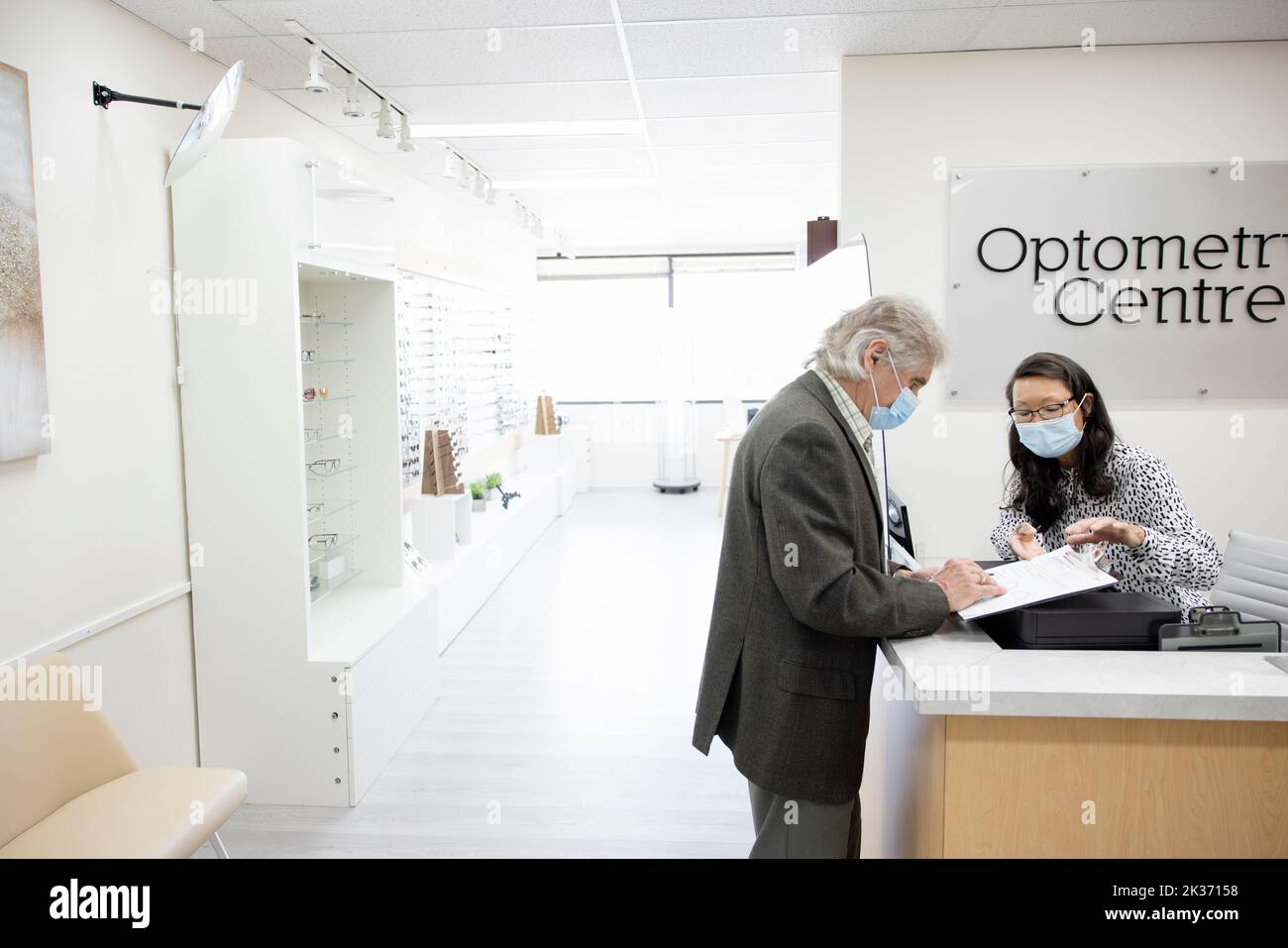 Optometry receptionist in face mask explaining paperwork to patient Stock Photo Alamy
