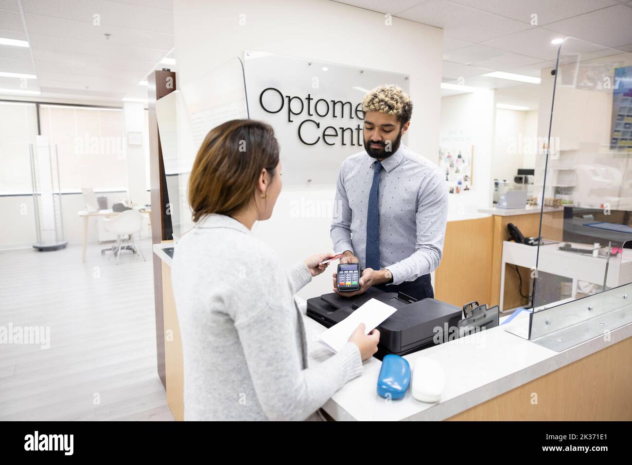 Patient with credit card paying receptionist in optometry center Stock Photo Alamy