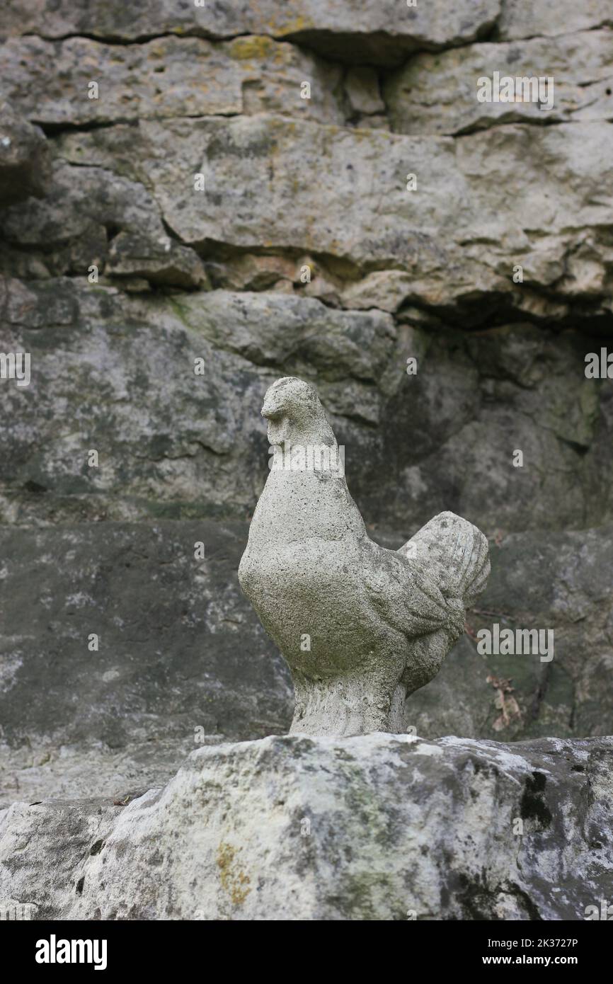 A stone statue of a chicken standing on the rocks Stock Photo - Alamy