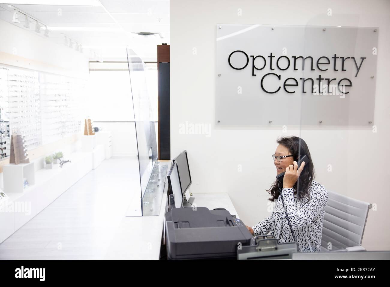 Female receptionist answering telephone in optometry center Stock Photo Alamy