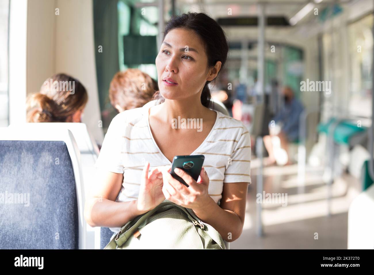 Asian woman using smartphone while sitting in tram Stock Photo